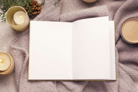 Book with aroma candles and cup of coffee on plaid