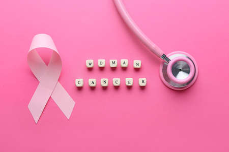 Pink ribbon, stethoscope and text WOMAN CANCER on color background