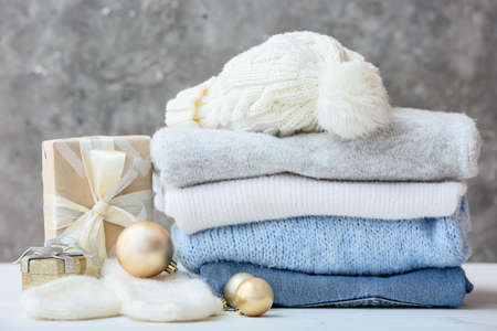 Stylish Christmas clothes with gift on table