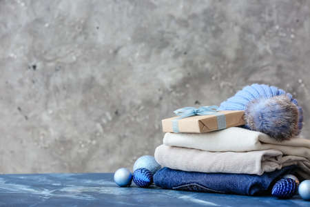 Stylish Christmas clothes with gift on table