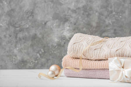Stylish Christmas clothes with gift on table