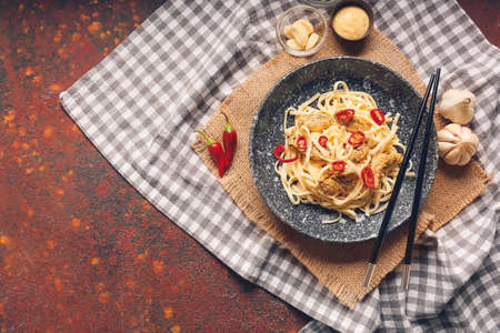 Plate with tasty noodles, chicken and chopsticks on grunge backgroundの写真素材