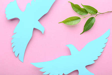Paper doves and olive branch on color background. International Day of Peace