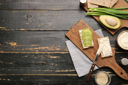 Crispbread with tasty cream cheese and avocado on wooden background