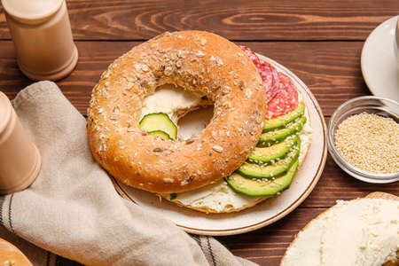 Bagel with tasty cream cheese on wooden background