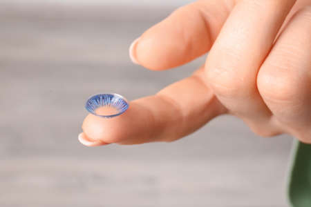 Female hand with contact lens on light backgroundの写真素材