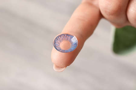 Female hand with contact lens on light backgroundの写真素材