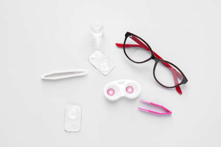 Eyeglasses, tweezers and container with contact lenses on light backgroundの写真素材