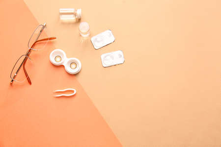 Eyeglasses, tweezers and container with contact lenses on color backgroundの写真素材