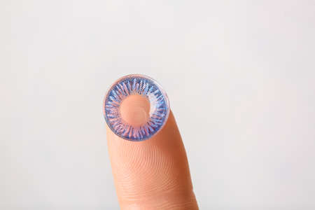 Female finger with contact lens on light backgroundの写真素材