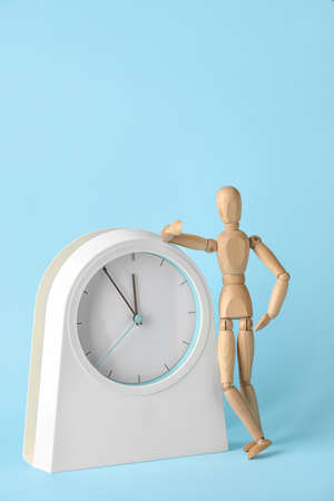 Wooden mannequin with clock on color background