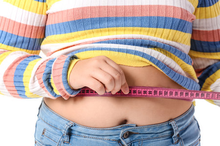 Overweight girl measuring her waist on white background, closeupの写真素材
