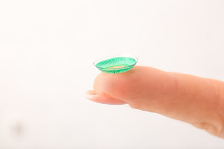 Female finger with contact lens on light backgroundの写真素材