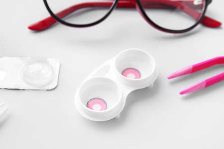 Eyeglasses, tweezers and container with contact lenses on light backgroundの写真素材