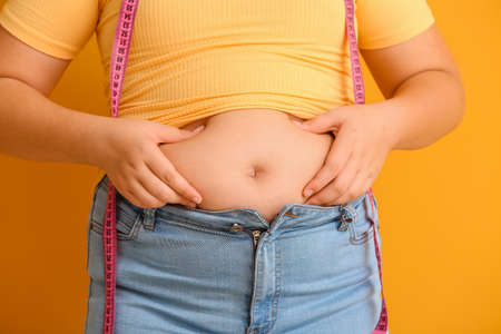 Overweight girl with measuring tape on color background, closeupの写真素材