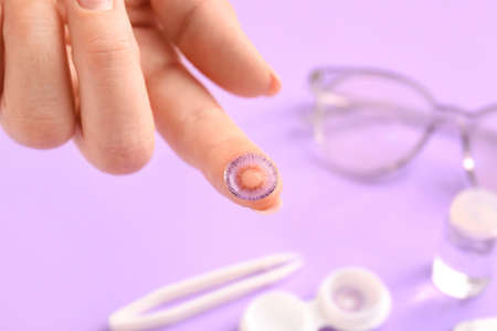Female hand with contact lens on color backgroundの写真素材