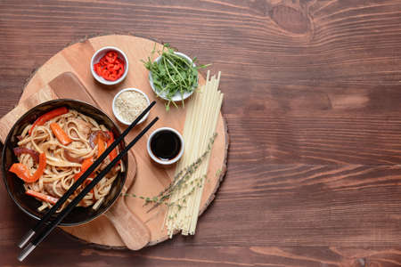 Plate with tasty noodles and meat on wooden background