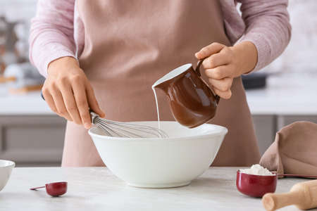 Woman making dough on table in kitchen