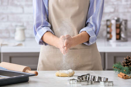 Woman making dough on table in kitchen