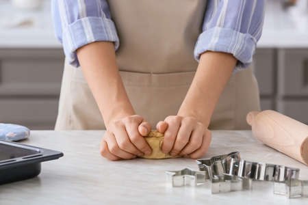 Woman making dough on table in kitchenの写真素材