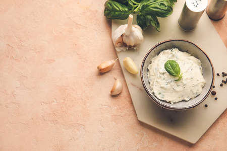 Bowl with tasty garlic butter and ingredients on color background