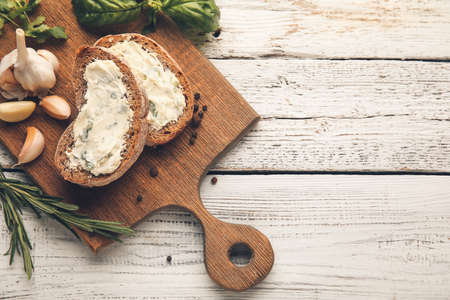 Board with slices of bread and garlic butter on light wooden backgroundの写真素材