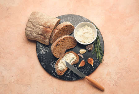 Fresh bread, garlic butter and ingredients on color backgroundの写真素材