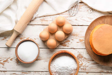 Tasty pumpkin pancakes with ingredients on table