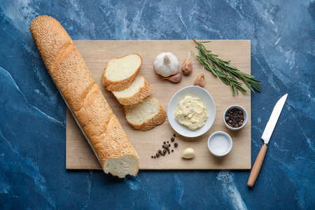 Fresh bread, garlic butter and ingredients on color background