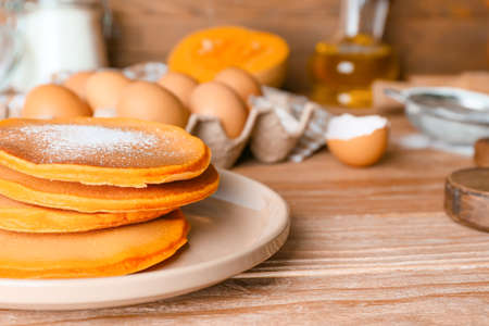 Tasty pumpkin pancakes on table