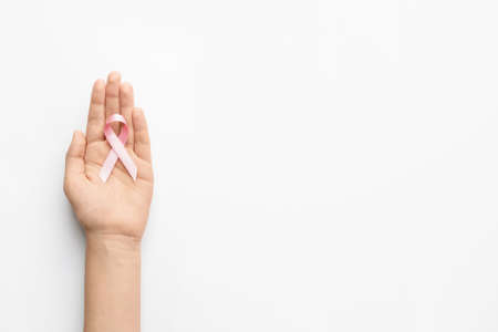 Female hand with pink ribbon on white background. Breast cancer awareness conceptの写真素材
