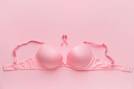 Pink ribbon and bra on color background. Breast cancer awareness conceptの写真素材