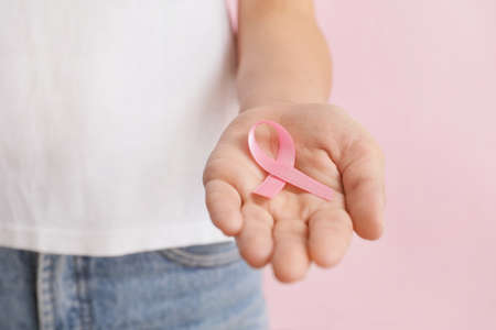 Woman with pink ribbon on color background, closeup. Breast cancer awareness conceptの写真素材