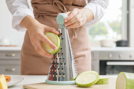 Woman grating zucchini in kitchen
