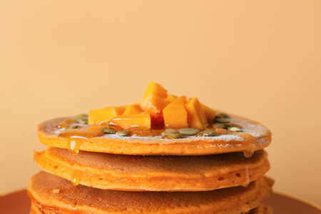 Plate with tasty pumpkin pancakes on color background, closeup