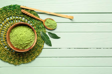 Bowl with powdered matcha tea, chashaku and spoon on color wooden backgroundの写真素材