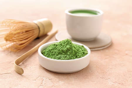 Bowl with powdered matcha tea on color background