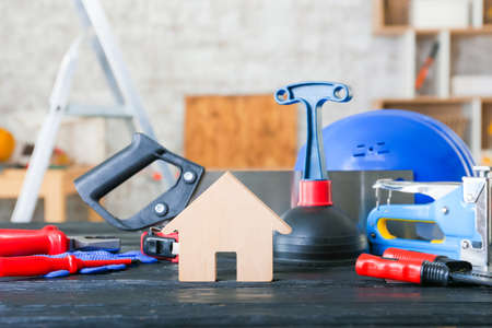 Figure of house with builder's supplies on wooden table