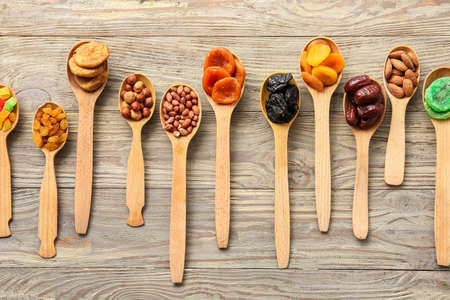 Spoons with different dried fruits and nuts on wooden backgroundの写真素材