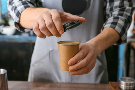 Barista with cup of hot coffee in cafe, closeup