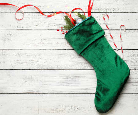 Composition with Christmas sock on white wooden background