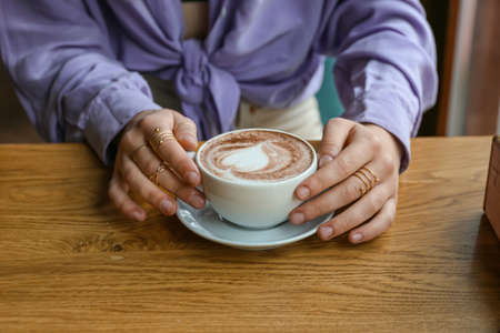 Woman drinking hot coffee in cafe, closeup