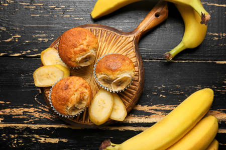 Tasty cupcakes and ripe bananas on dark wooden backgroundの写真素材