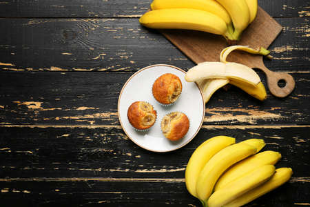 Tasty cupcakes and ripe bananas on dark wooden backgroundの写真素材
