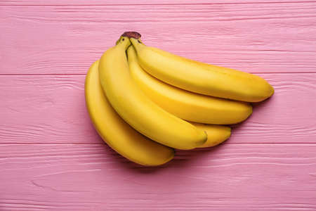 Ripe bananas on color wooden backgroundの写真素材