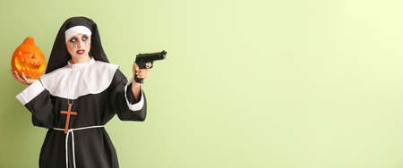 Woman dressed for Halloween as nun with gun and pumpkin on color background