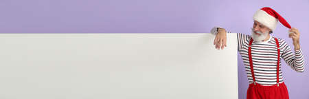 Santa Claus with blank poster on color background with space for text