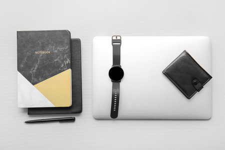 Modern smart watch, laptop and notebooks on light background