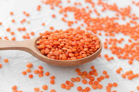 Spoon with raw lentils on table