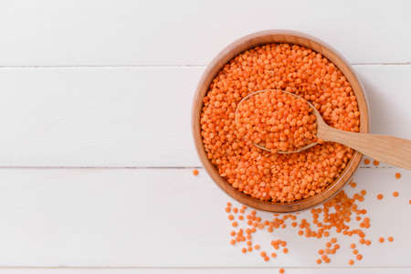 Bowl and spoon with raw lentils on tableの写真素材